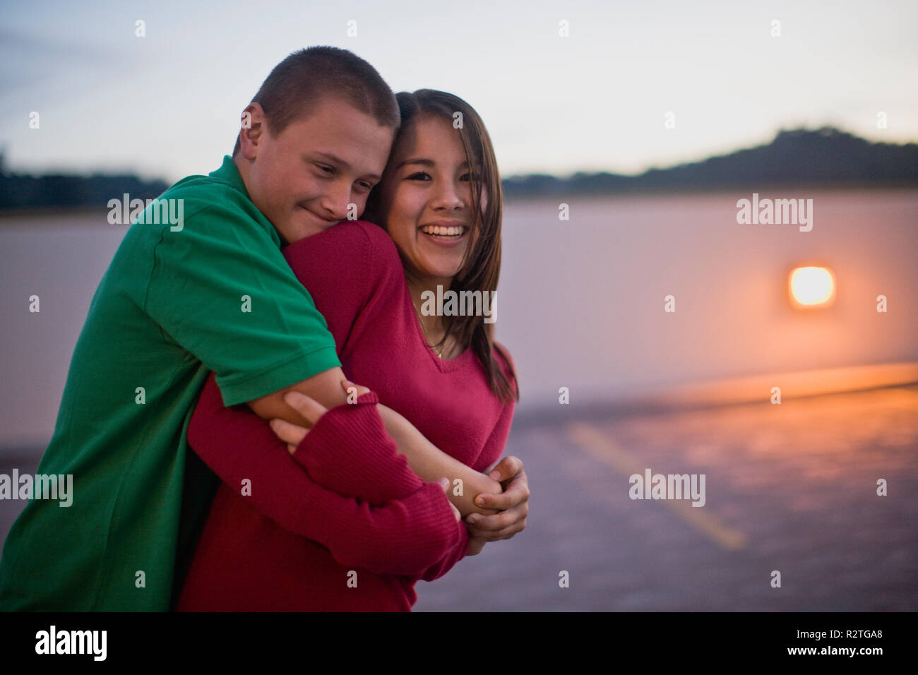 Teenage couple hugging in an empty parking lot Stock Photo