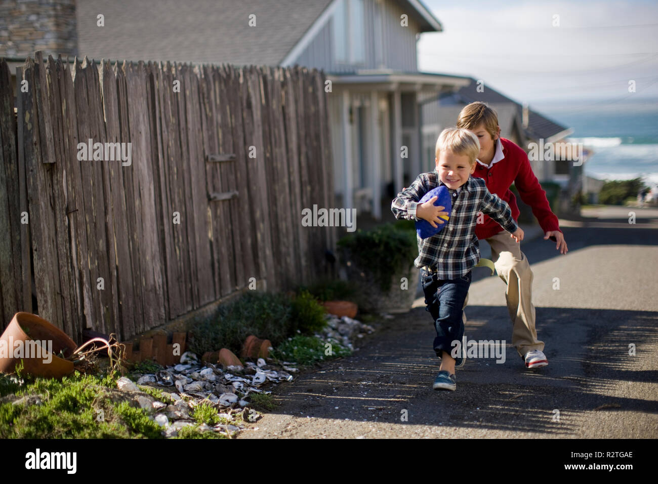 Two brothers playing with a football on the street. Stock Photo