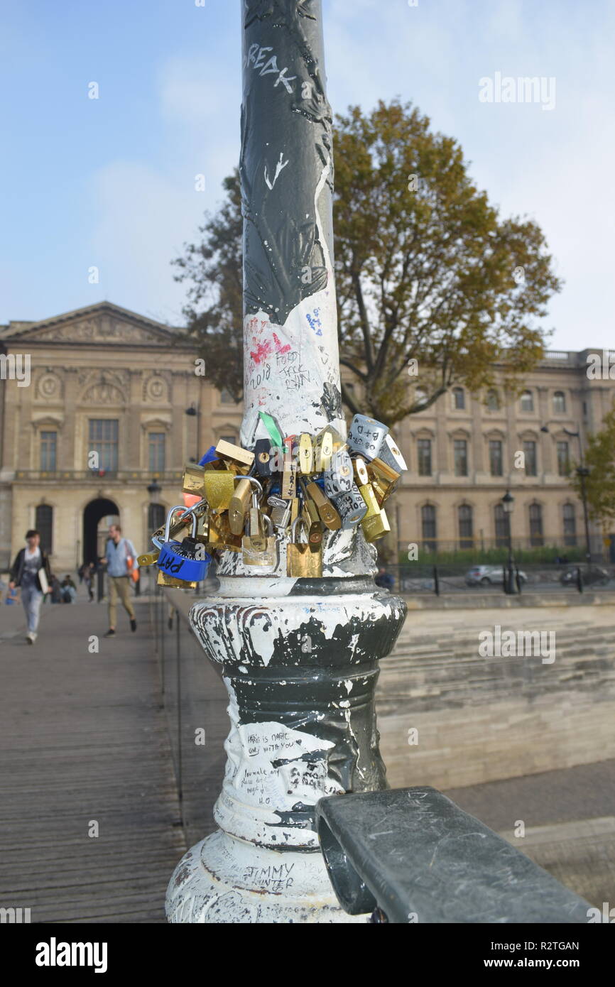 Love padlock on Pont des Arts footbridge on the Seine River and People walking across a pedestrian bridge over the RiverSeine facing the Louvre museum Stock Photo