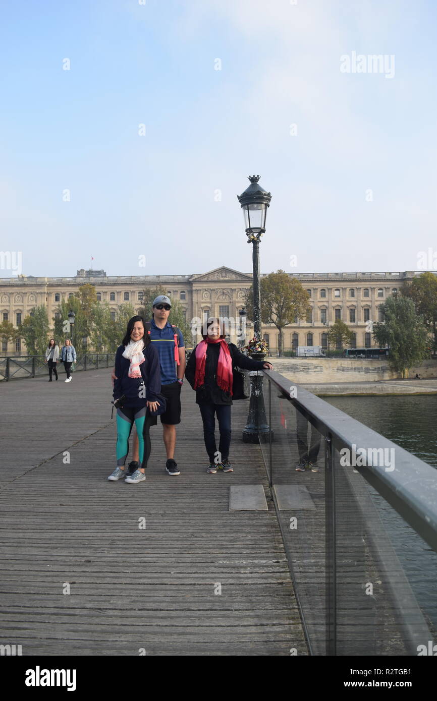 Peoples on Pont des Arts footbridge on the Seine River and People walking across a pedestrian bridge over the River Seine facing the Louvre museum Stock Photo