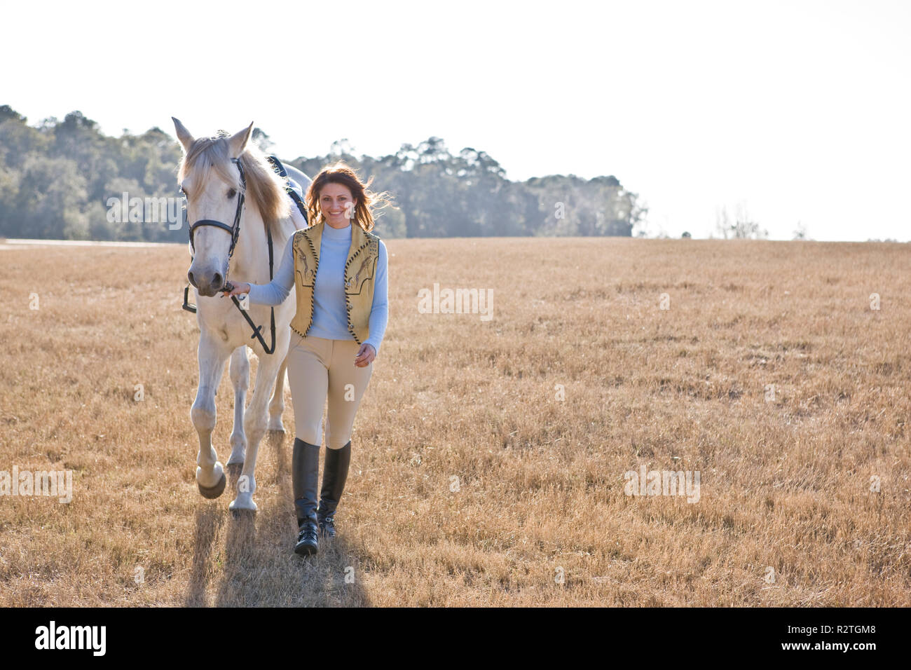 Woman walking with her horse across a field Stock Photo