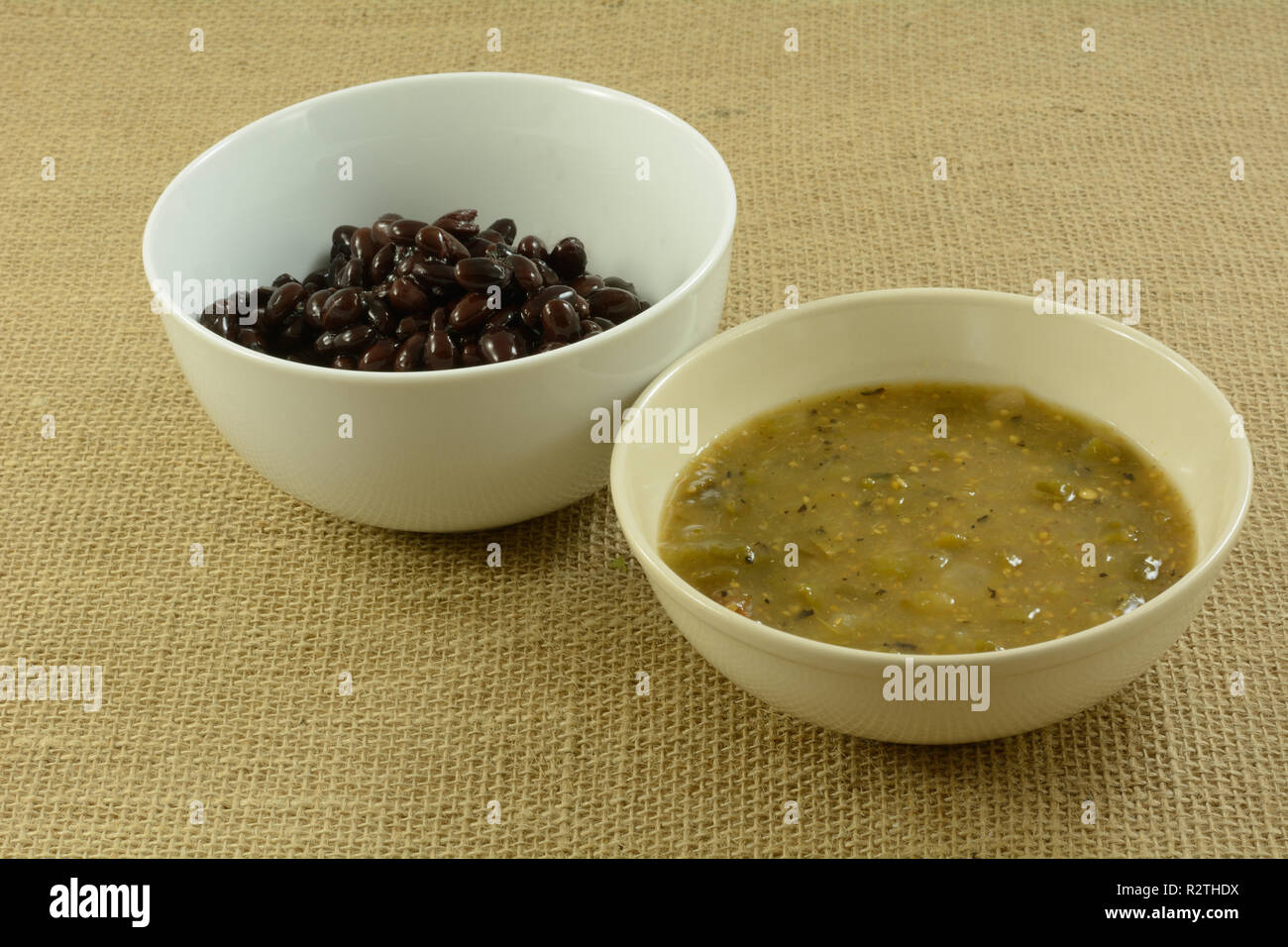 Ingredients for making Mexican food of black beans and salsa verde in white bowls Stock Photo