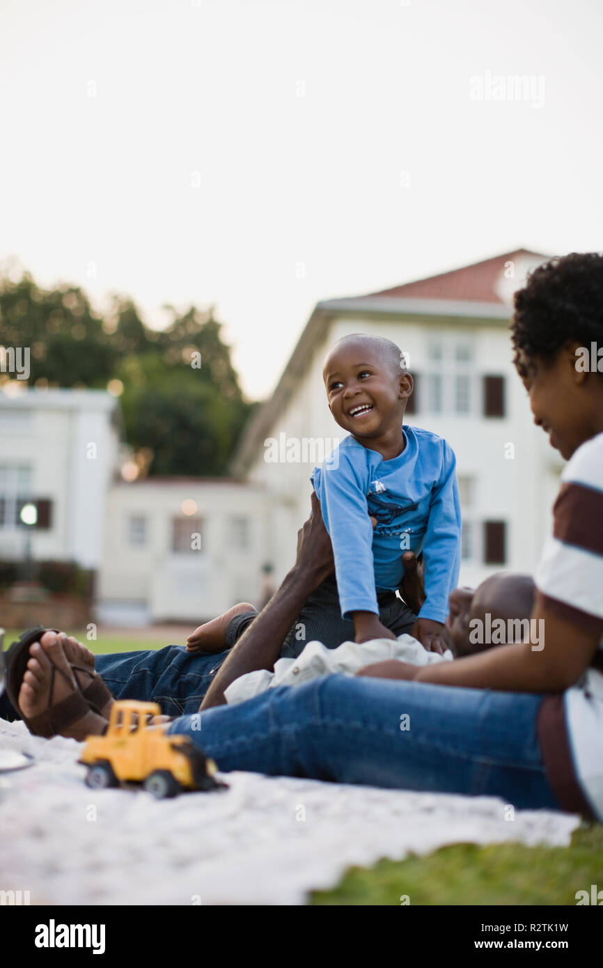 Young boy playing with his young adult father while picnicking with his mother. Stock Photo