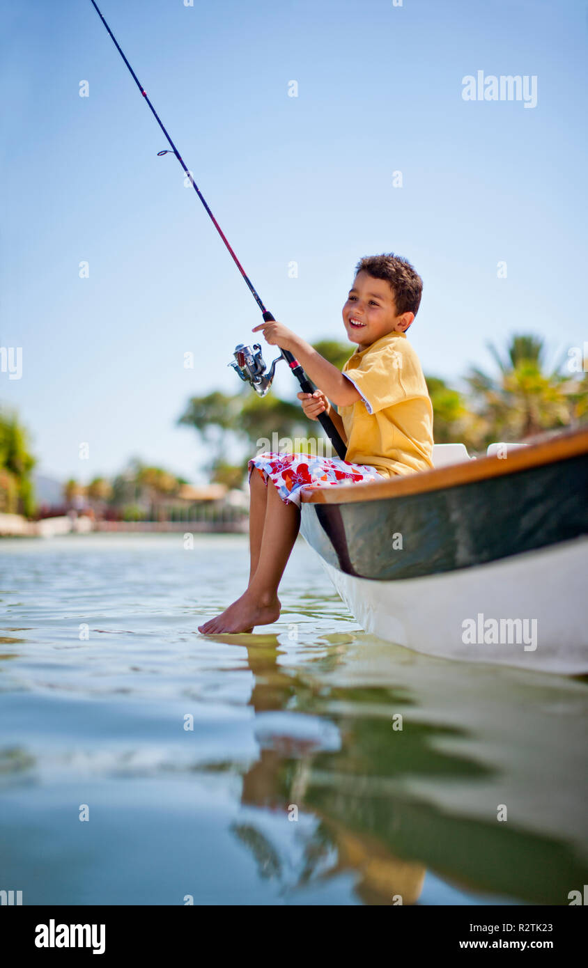 Happy young boy fishing from a small boat in a tropical river Stock Photo -  Alamy