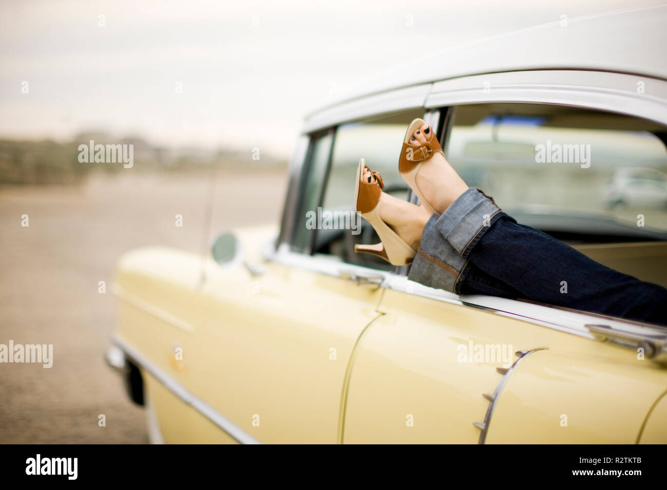 Young woman's legs sticking out of a car Stock Photo
