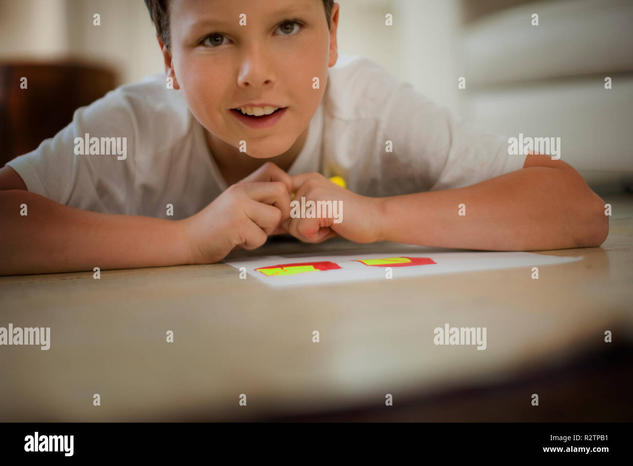 Boy lying down coloring in pictures. Stock Photo