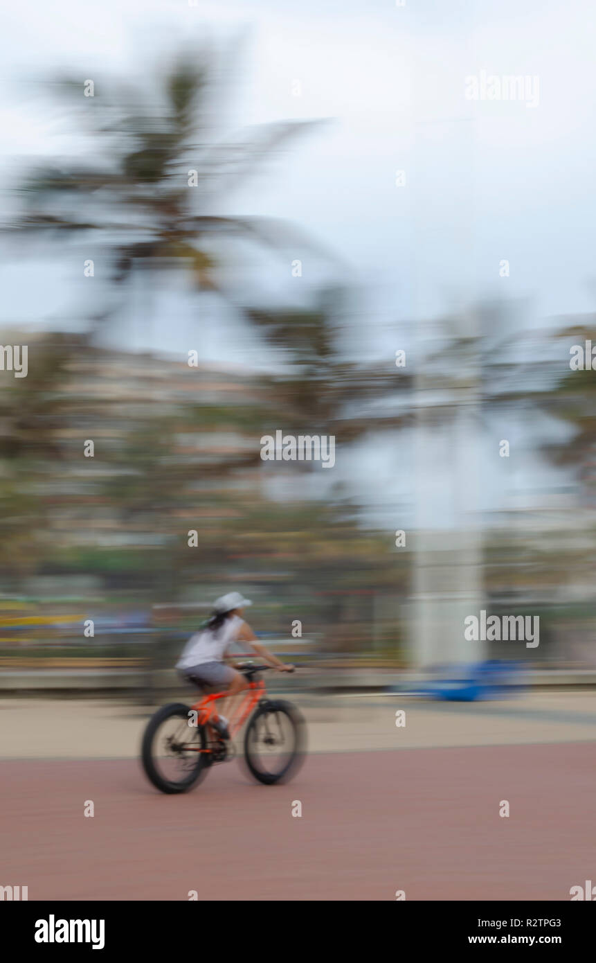 An early morning fitness fan cycles on Durban's beachfront boardwalk. Stock Photo