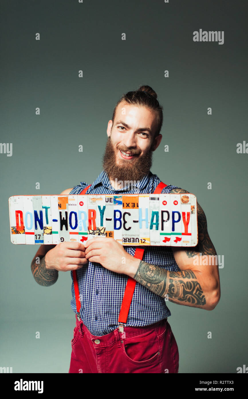 Portrait confident hipster man holding  Dont Worry Be Happy  license plates Stock Photo