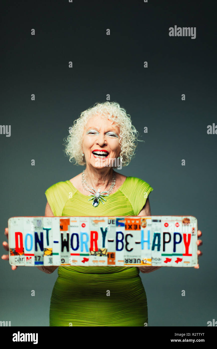 Portrait happy senior woman holding  Dont Worry Be Happy  license plates Stock Photo