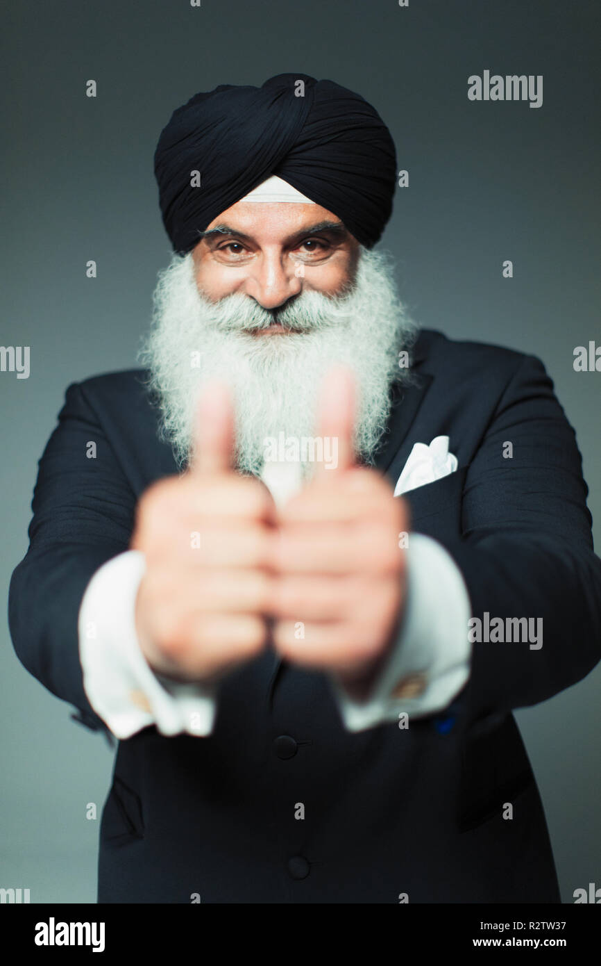 Portrait enthusiastic well-dressed senior man wearing turban, gesturing thumbs-up Stock Photo