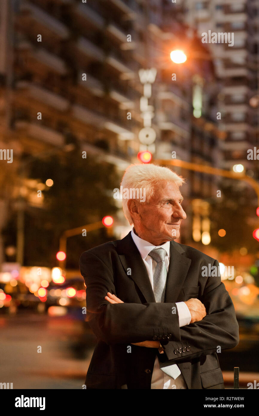 Mature businessman with his arms crossed looks away as he poses for a ...