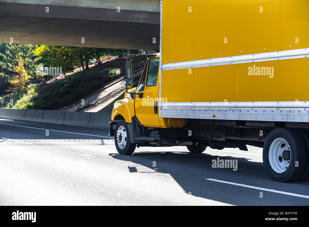 Yellow small size compact rig semi truck with box trailer transporting local commercial cargo