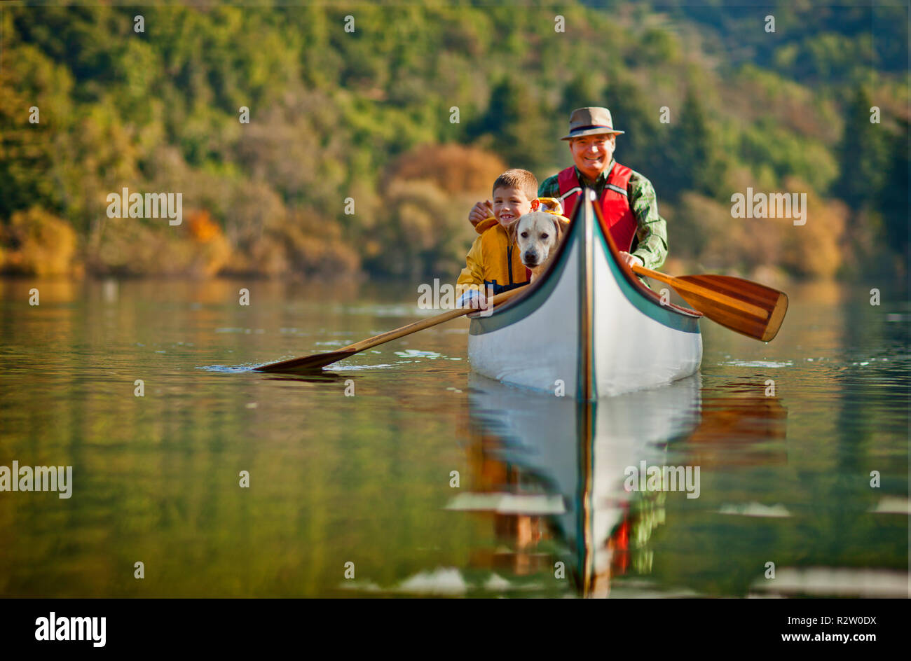 Grandfather canoeing on river with grandson. Stock Photo