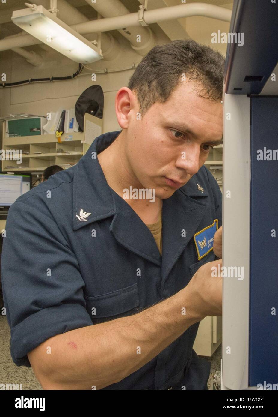 MEDITERRANEAN SEA (Nov. 6, 2018) Electronics Technician 3rd Class Artemio Gomez conducts maintenance on a printer aboard the San Antonio-class amphibious transport dock ship USS Anchorage (LPD 23) in the Mediterranean Sea, Nov. 6, 2018. Anchorage and embarked 13th Marine Expeditionary Unit are deployed to the U.S. 6th Fleet area of operations as a crisis response force in support of regional partners as well as to promote U.S. national security interests in Europe and Africa. Stock Photo
