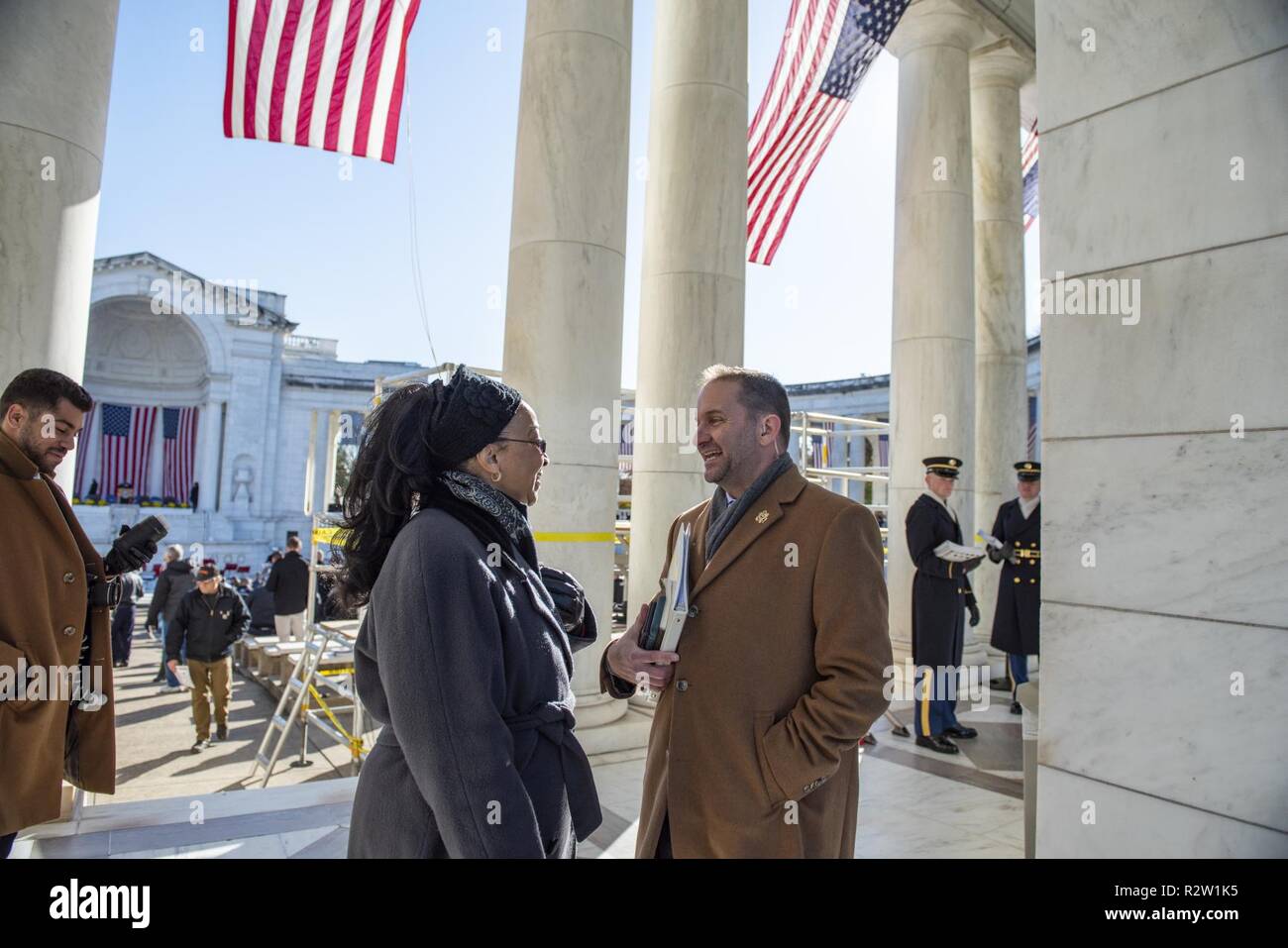 Adrienne Combs (center), deputy public affairs officer, Military District of Washington; speaks with Micheal Migliara (right), director of operations, Arlington National Cemetery, during the Veterans Day Observance in the Memorial Amphitheater at Arlington National Cemetery, Arlington, Virginia, Nov. 11, 2018. Stock Photo