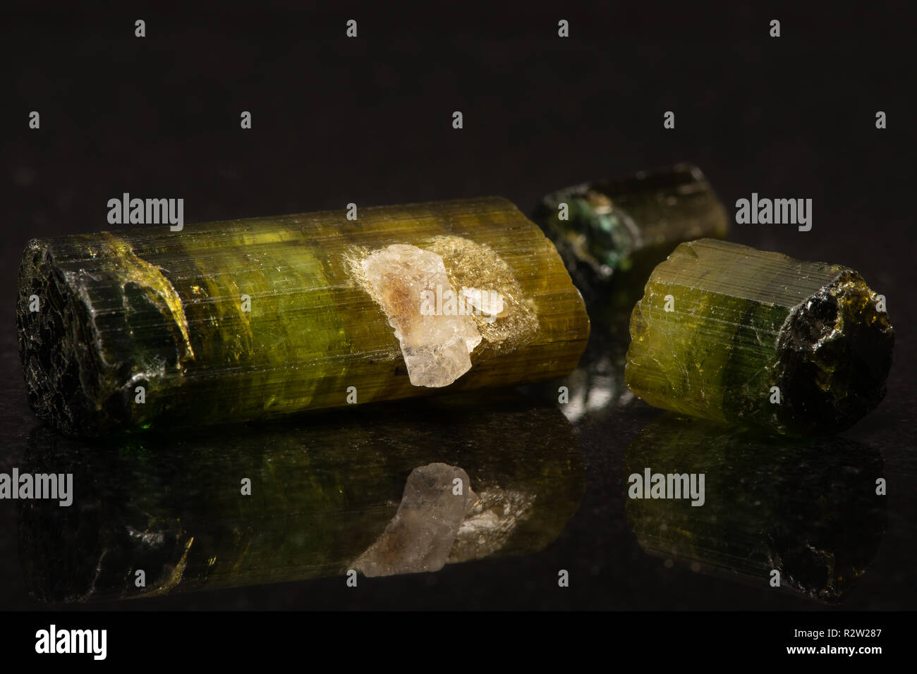 Several tourmaline crystals on a dark reflective background. Stock Photo
