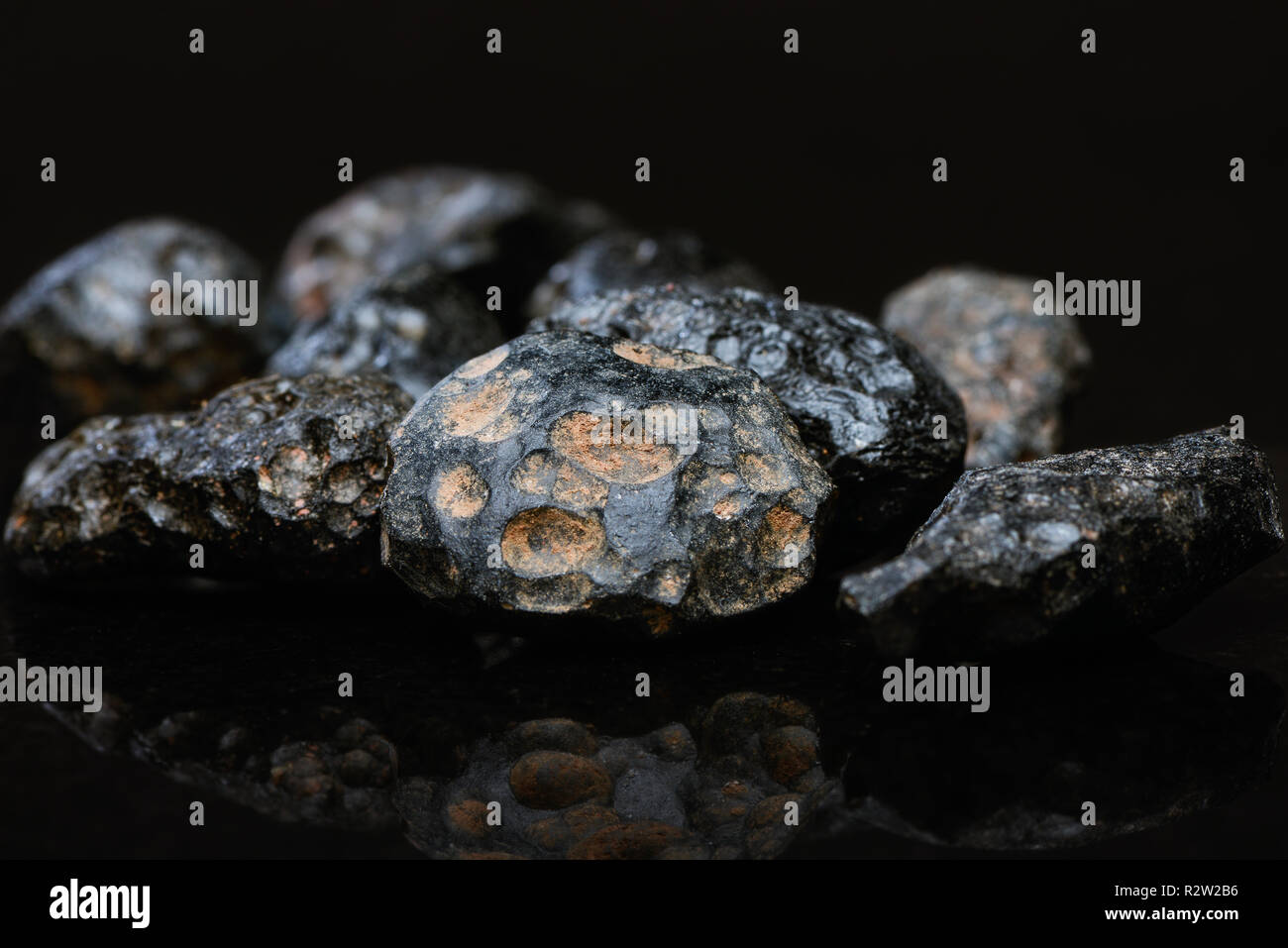 Closeup of several pieces of tektite on a dark reflective background. Stock Photo