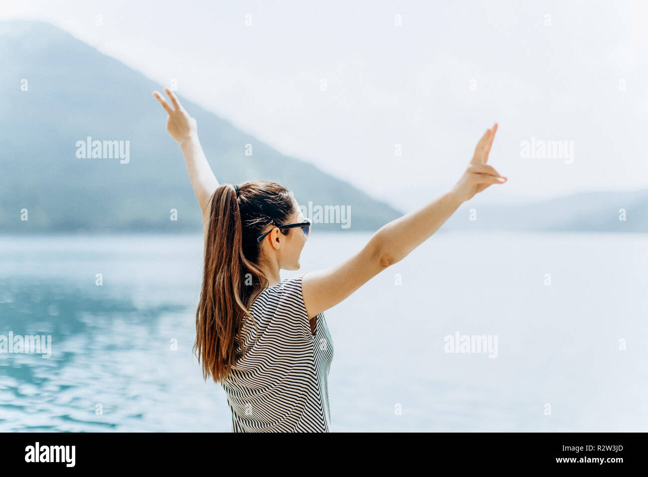 The girl on the background of the sea raises her hands up and shows how ...