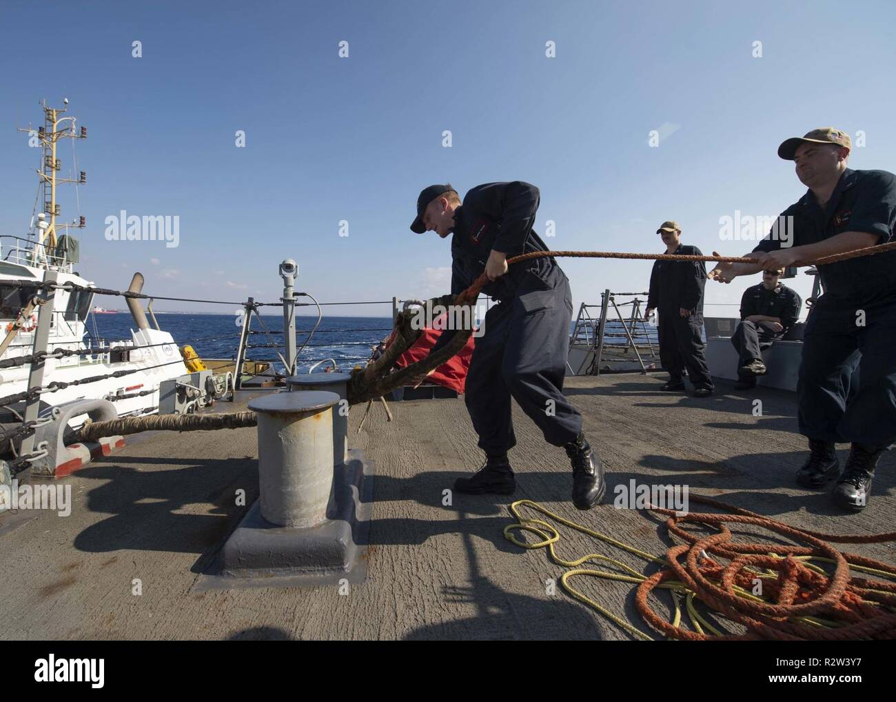 LARNACA, Cyprus (Nov. 9, 2018) Sailors heave a mooring line connected to a tugboat aboard the Arleigh Burke-class guided-missile destroyer USS Arleigh Burke (DDG 51) as the ship arrives at Larnaca, Cyprus for a scheduled port visit Nov. 9, 2018. Arleigh Burke, homeported at Naval Station Norfolk, is conducting naval operations in the U.S. 6th Fleet area of operations in support of U.S. national security interests in Europe and Africa. Stock Photo