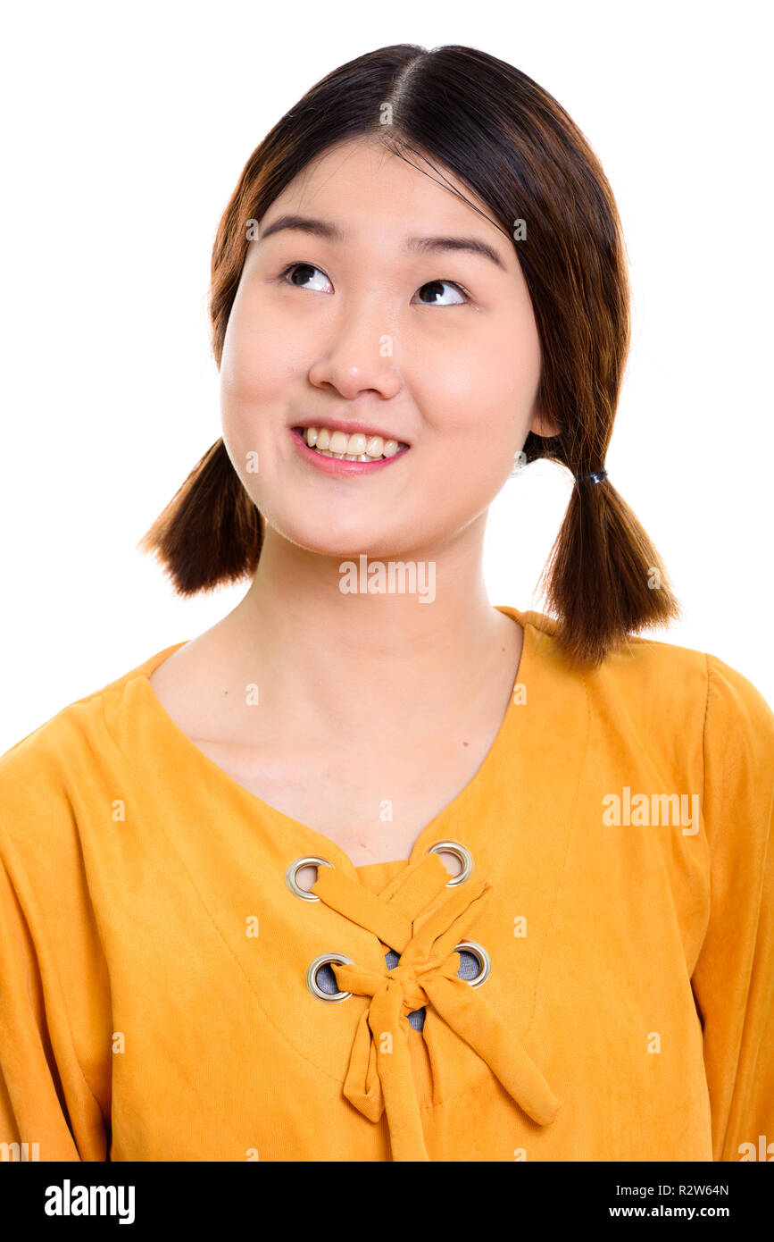 Face of young happy Asian woman smiling while thinking Stock Photo