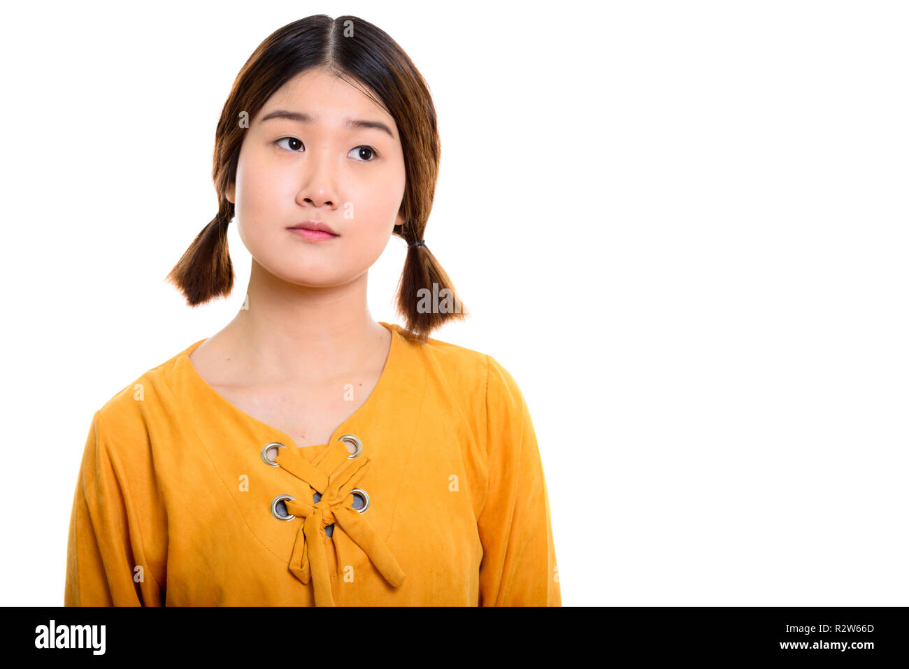 Studio shot of young beautiful Asian woman thinking Stock Photo - Alamy