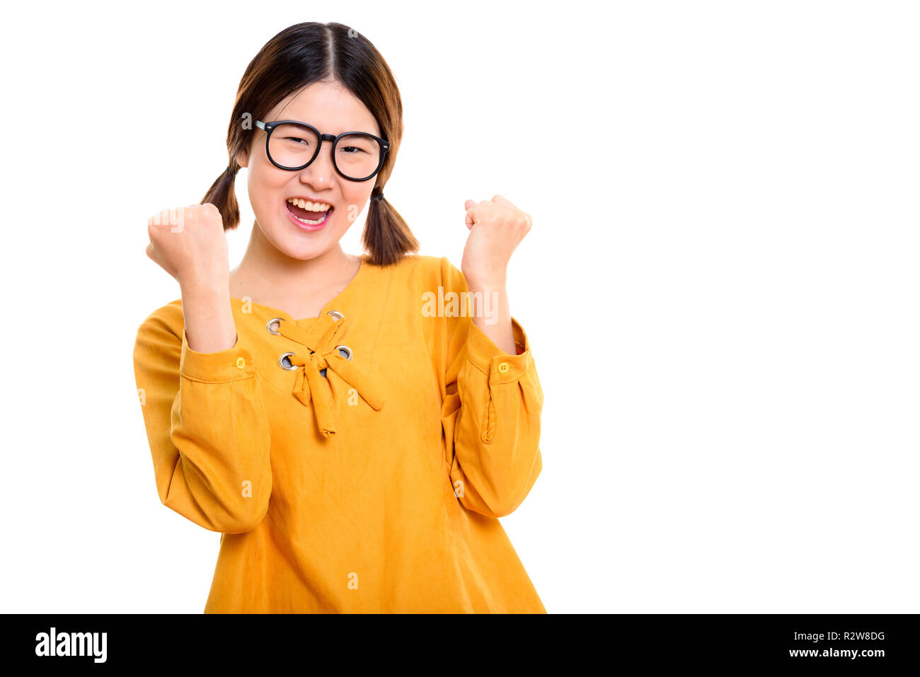 Studio shot of young happy Asian woman cheering with both arms r Stock Photo