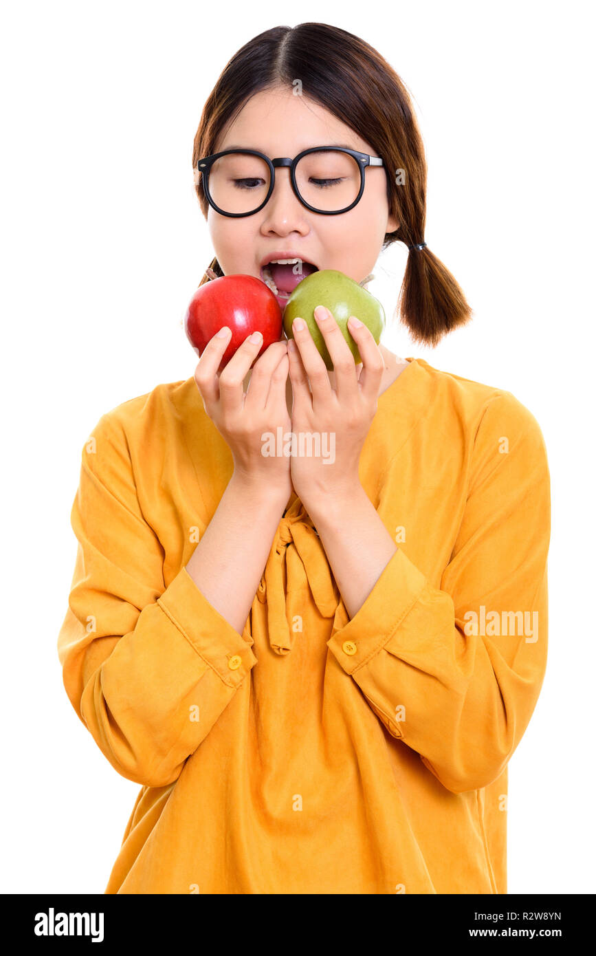 Studio shot of young beautiful Asian woman eating red apple and  Stock Photo