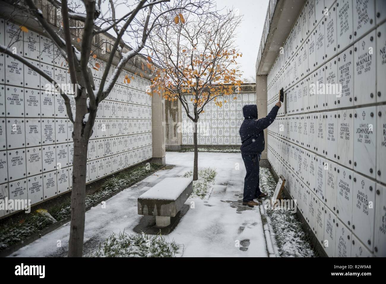 A cemetery caretaker cleans off an open niche cover  in Columbarium Court 7 at Arlington National Cemetery, Arlington, Virginia, Nov. 15, 2018. This was the first snow fall of the season. Stock Photo