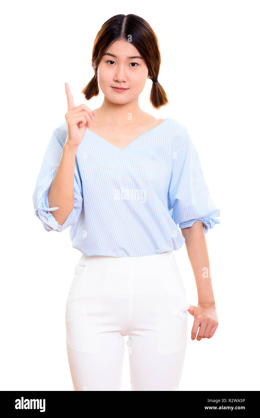 Studio shot of young beautiful Asian woman pointing finger up  Stock Photo