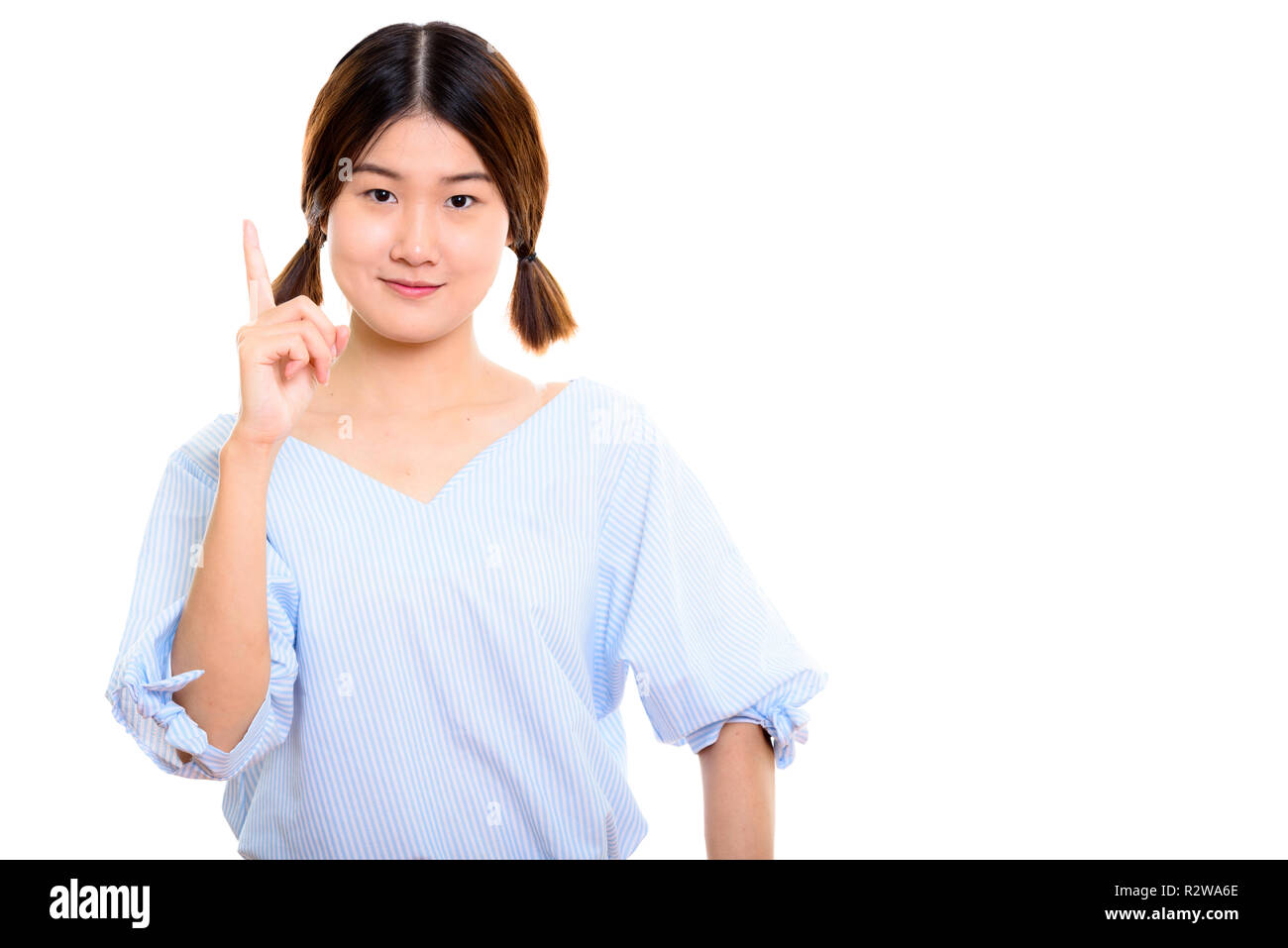 Studio shot of young beautiful Asian woman pointing finger up  Stock Photo