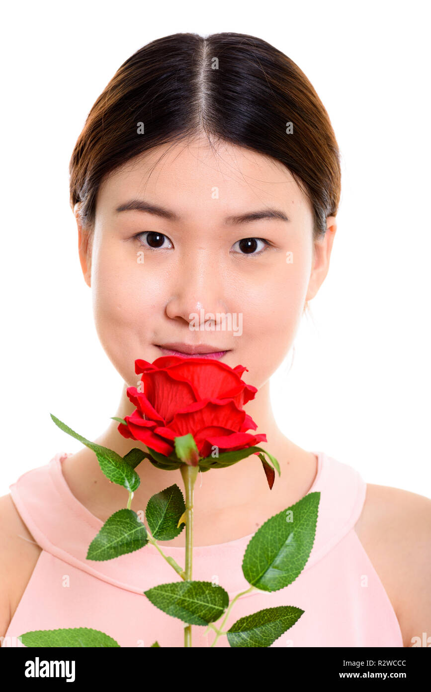 Face of young beautiful Asian woman holding red rose Stock Photo - Alamy
