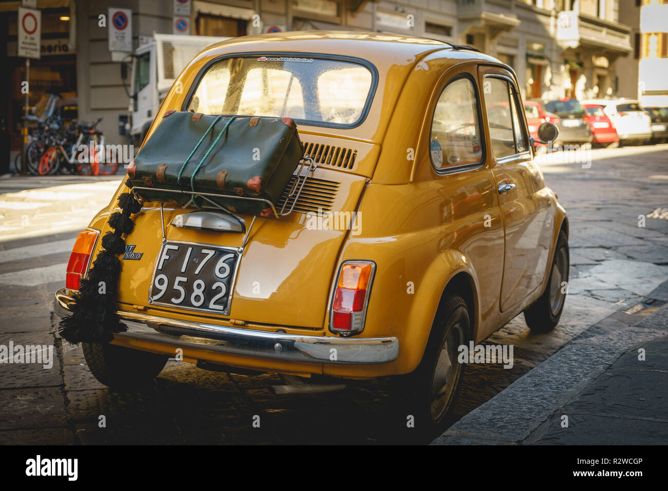 Florence, Italy - February, 2019. Yellow vintage Fiat 500 parked in the street of the historical town centre. Stock Photo