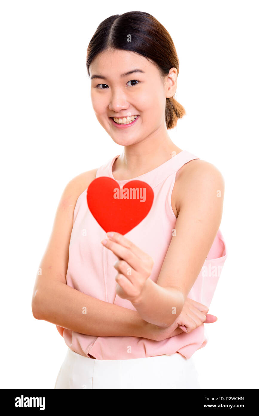 Studio shot of young happy Asian woman smiling while holding red Stock ...