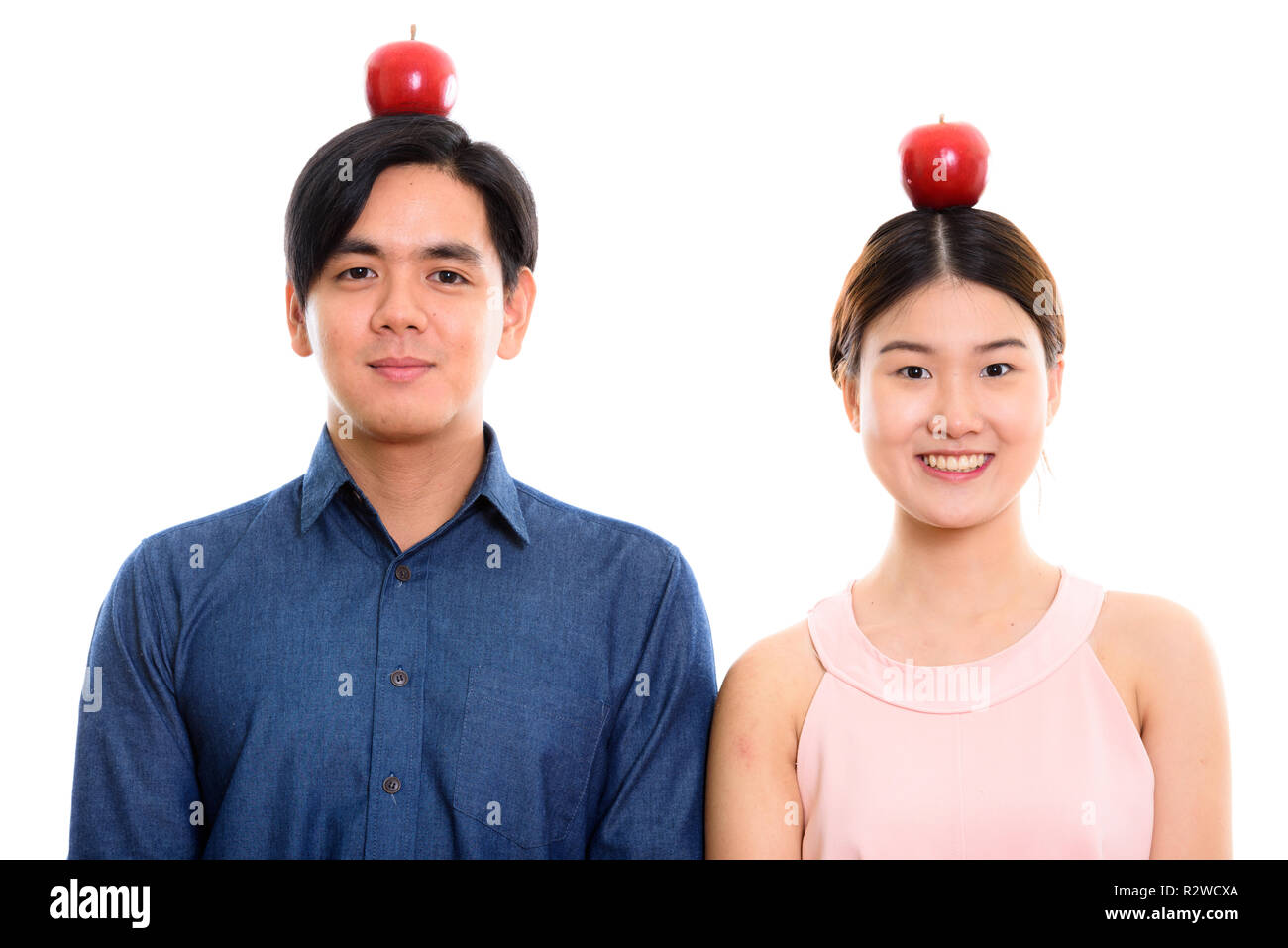 Studio shot of young happy Asian couple smiling with red apple o Stock Photo