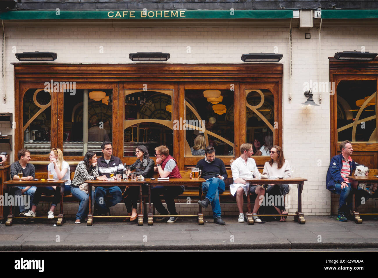 London, UK - February, 2019. People having drinks outside a coffee shop in Soho. Stock Photo