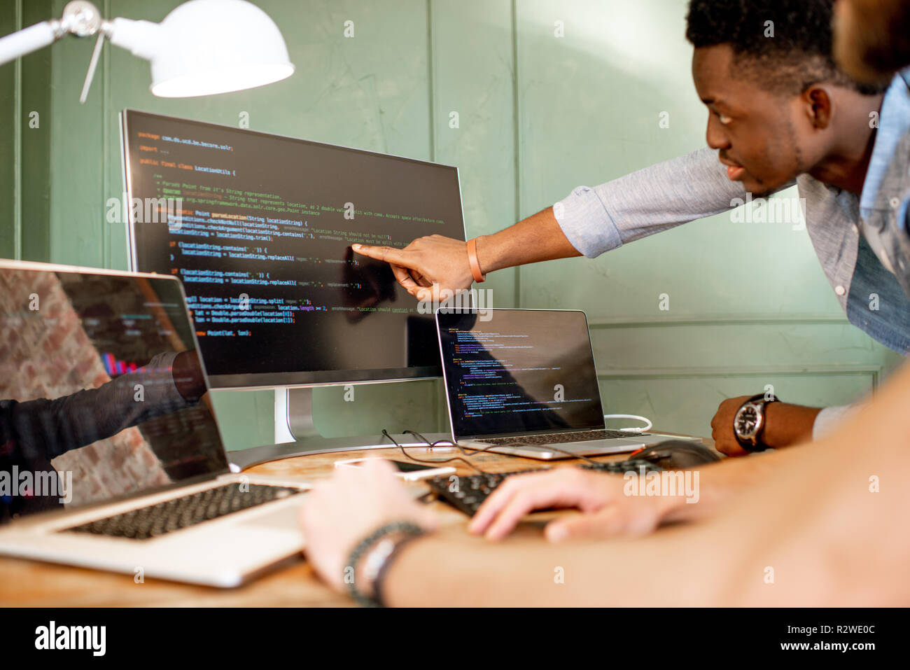 Two young programmers working with program code sitting at the ...