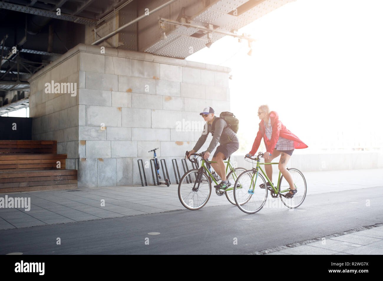 Side image of sportive woman and man riding bike through underpass Stock Photo