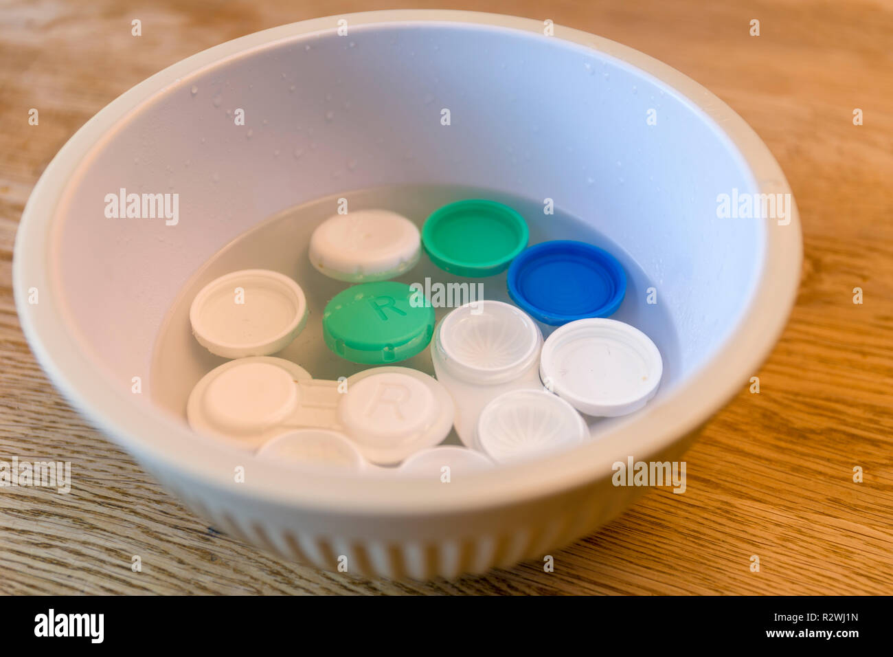 Several contact lens cases being cleaned and sterilised in bowl with just boiled steaming hot water Stock Photo