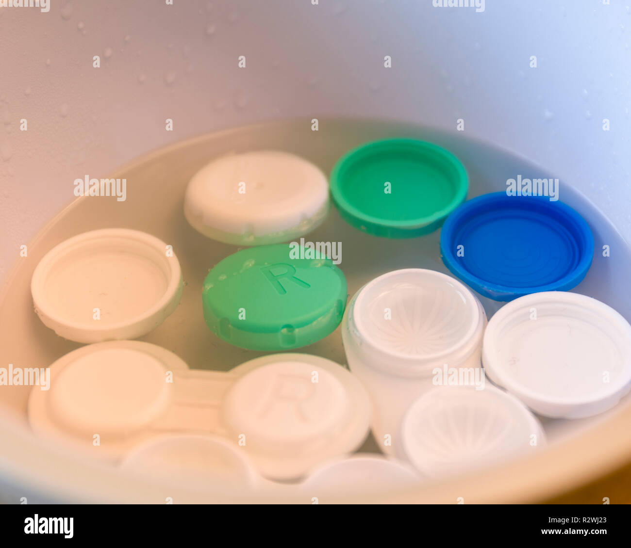 Several contact lens cases being cleaned and sterilised in bowl with just boiled steaming hot water Stock Photo