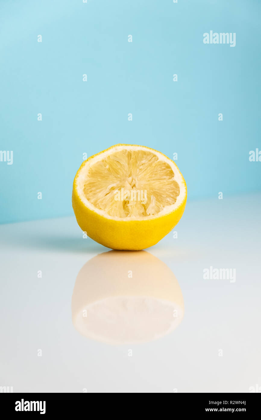 Half of squezzed lemon on white table. Minimalistic image of yellow citrus on bright  studio background Stock Photo