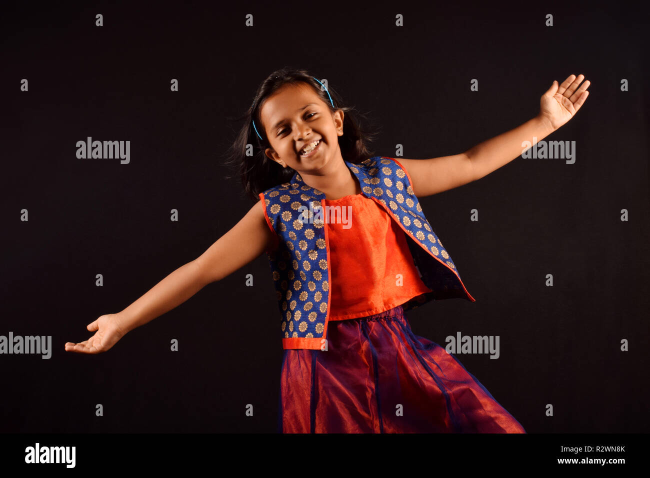 Little Girl in Indian attire with cute smile and outstretched arms posing in front of camera. Pune, Maharashtra Stock Photo
