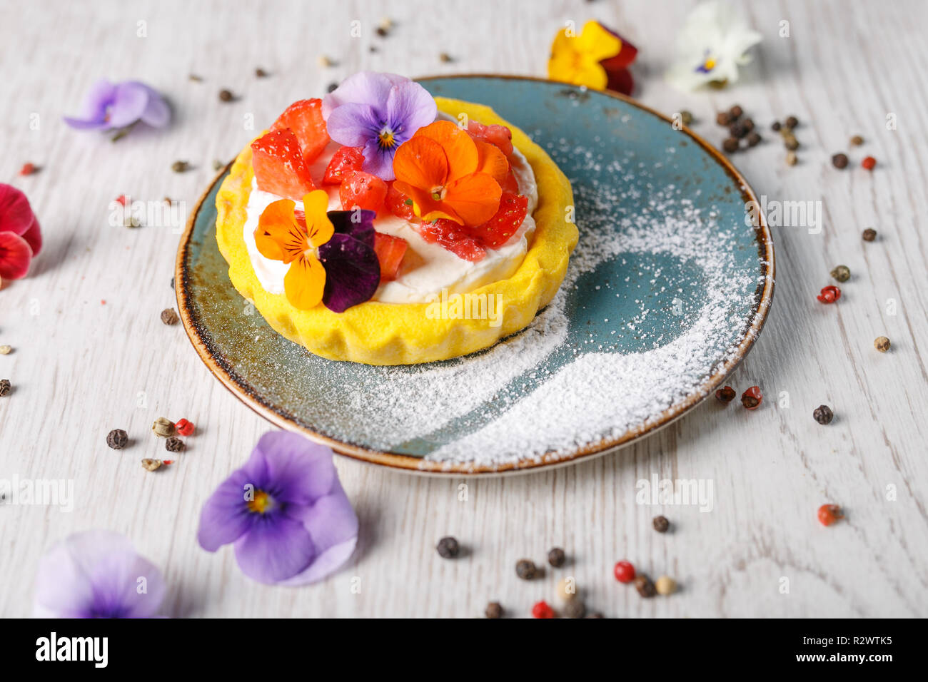 Strawberry Tart Garnished With Edible Flowers On A Blue Plate Stock Photo Alamy