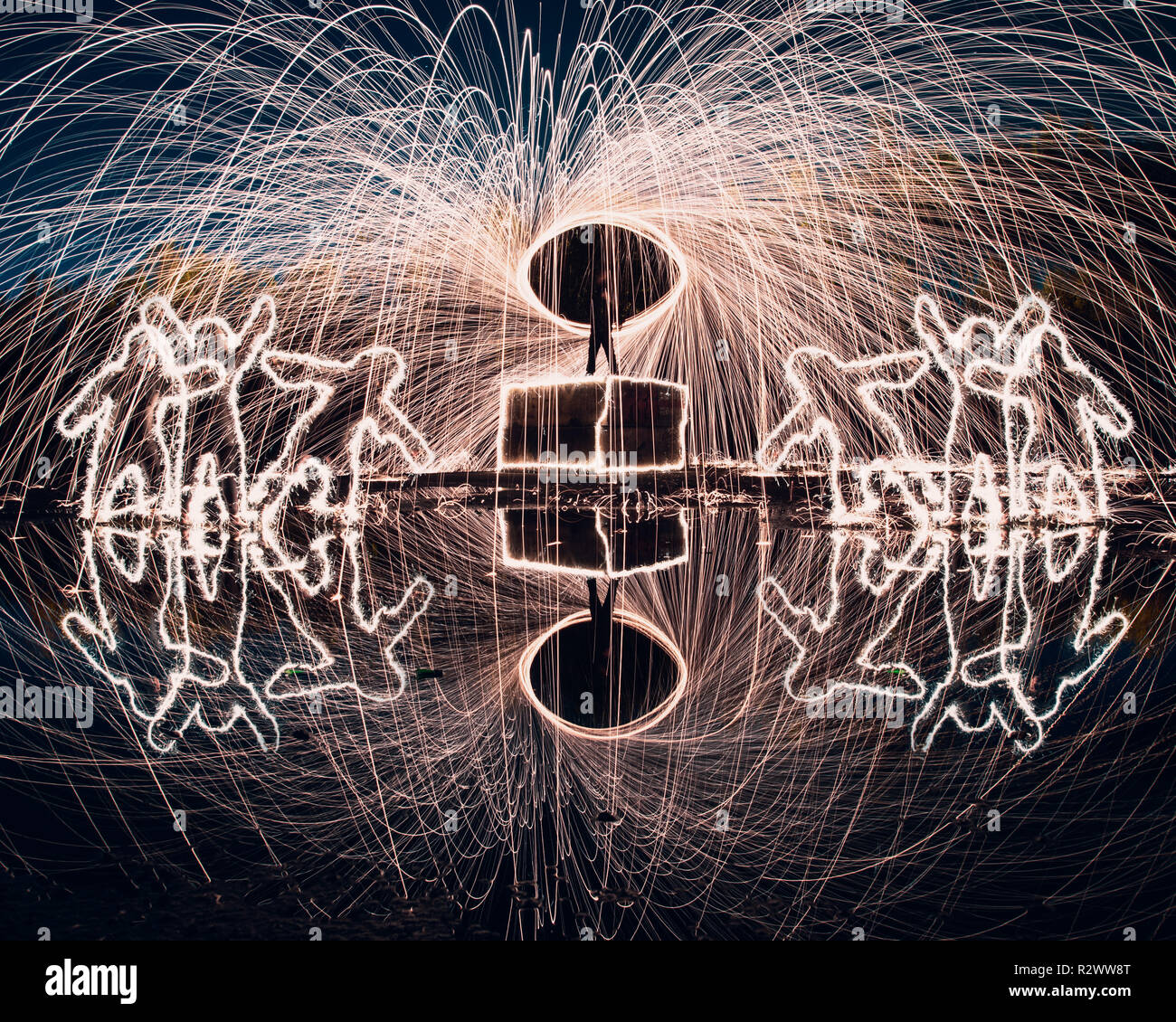 Steel wool spinning and light painting with reflections and people shaped from sparklers Stock Photo