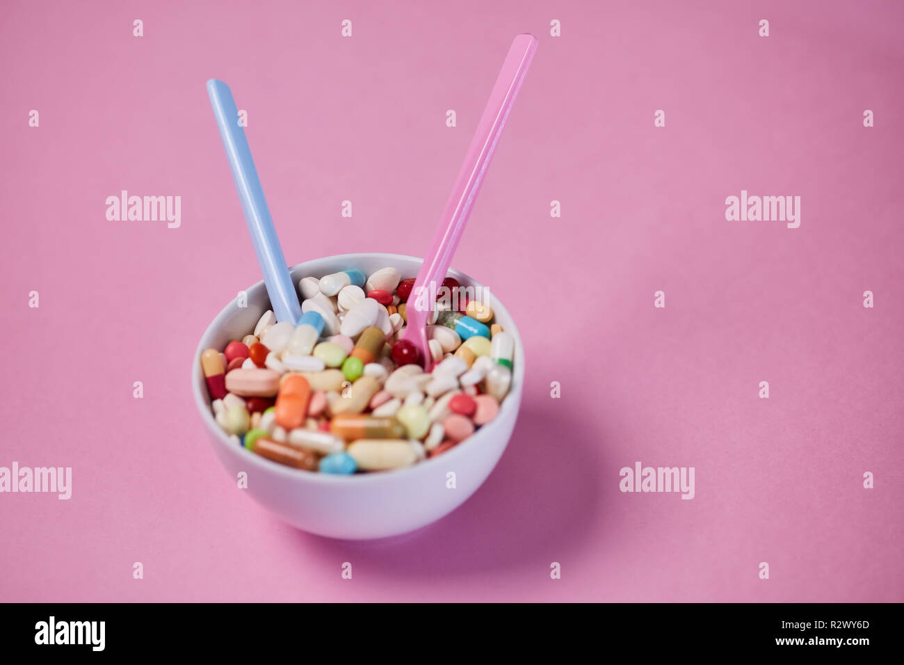 Colorful medicine with two spoons in a cup as drug addiction concept