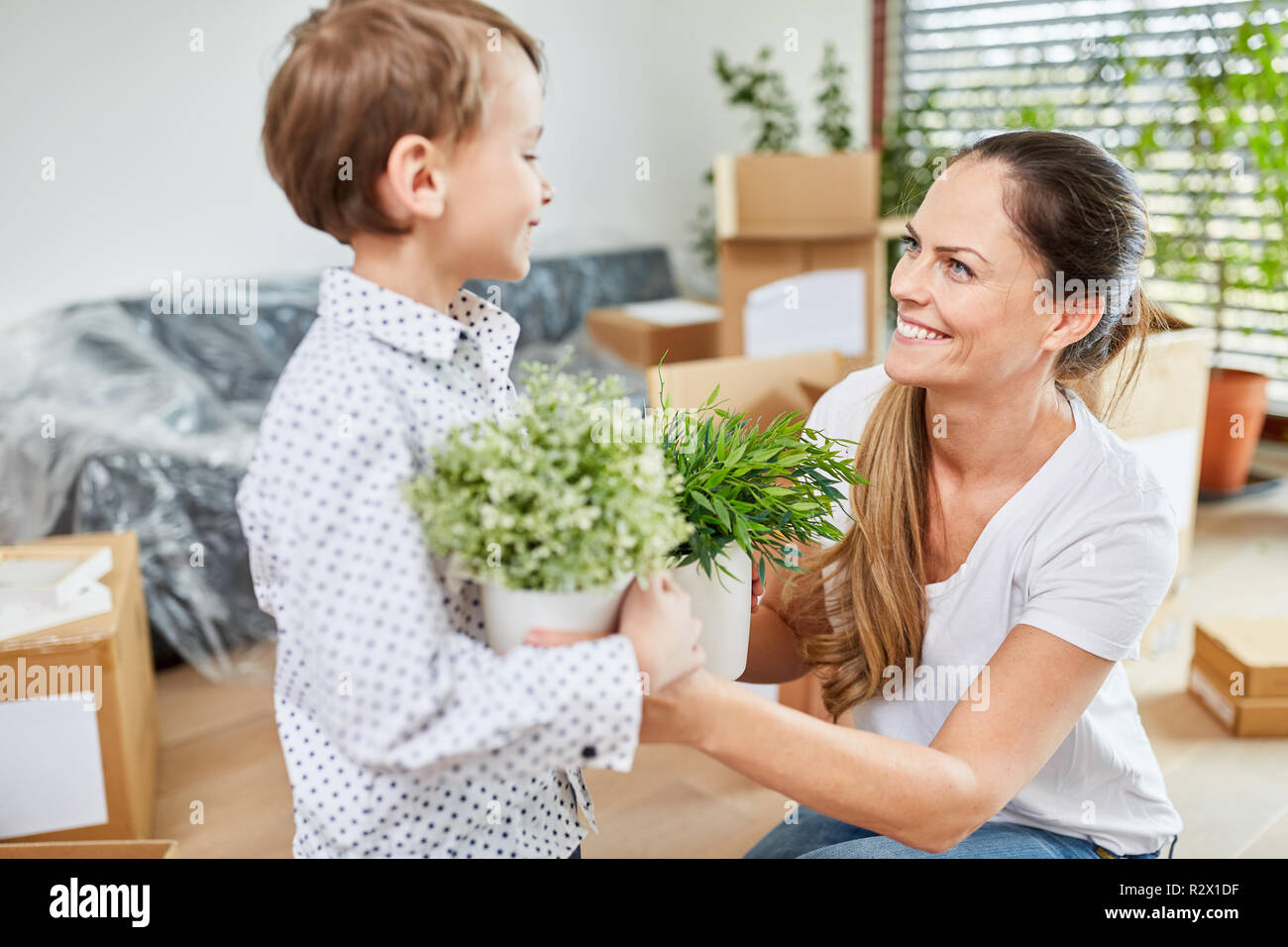 Happy mother and son with plants on move to new house in teamwork Stock Photo