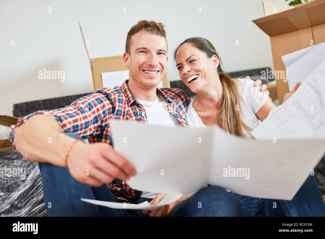 Laughing young couple with blueprint looking forward to the new house as a home Stock Photo