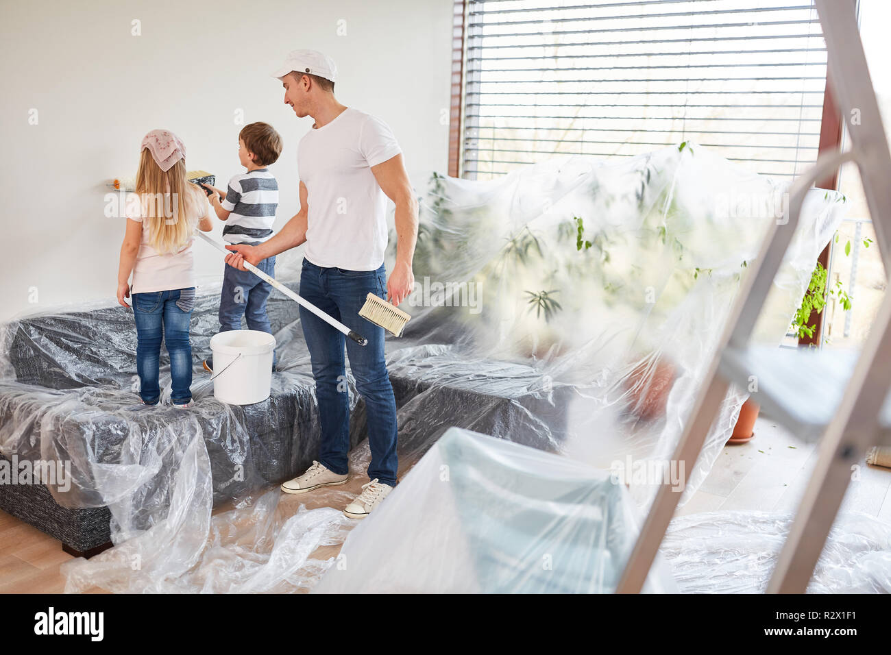 Father helps children to paint a wall while renovating before moving ...