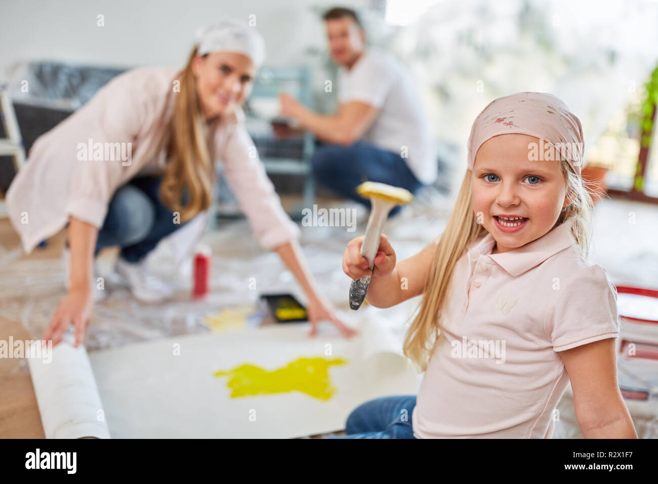 Little girl has fun while painting with family in new home Stock Photo