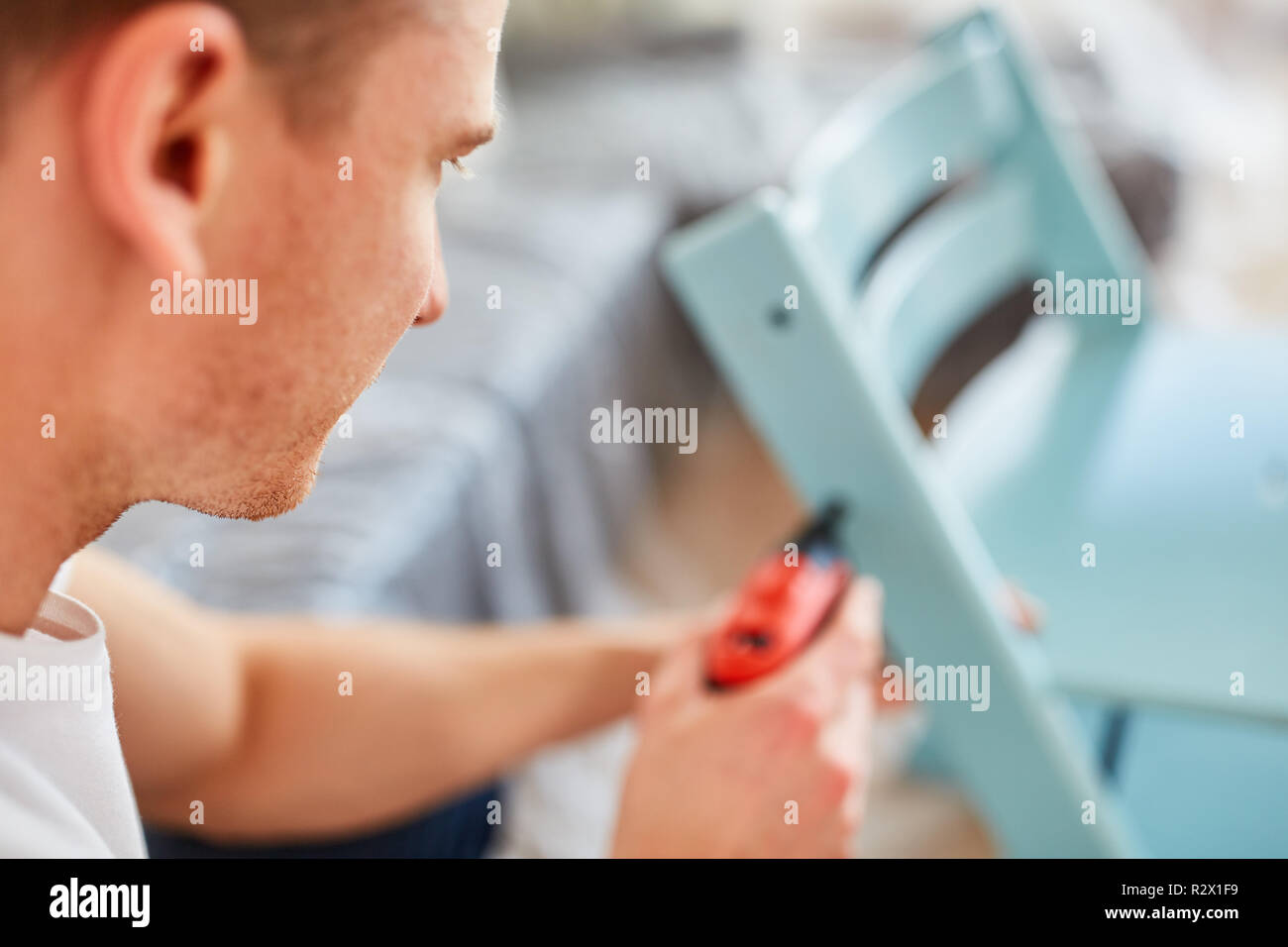 Man as a home improvement uses a drill screwdriver to assemble a chair ...