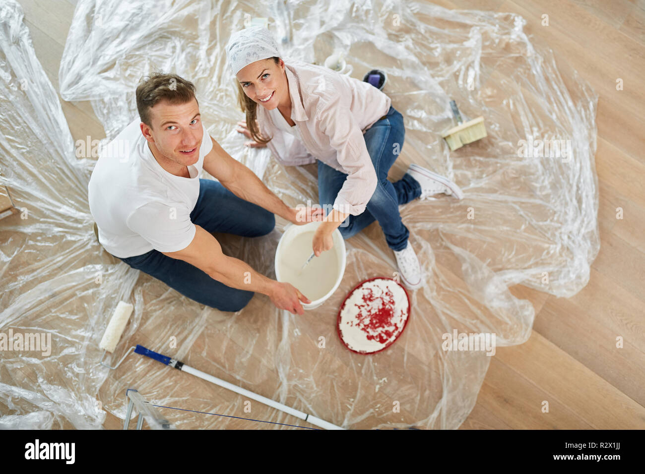 Happy couple renovating while mixing paint before moving Stock Photo